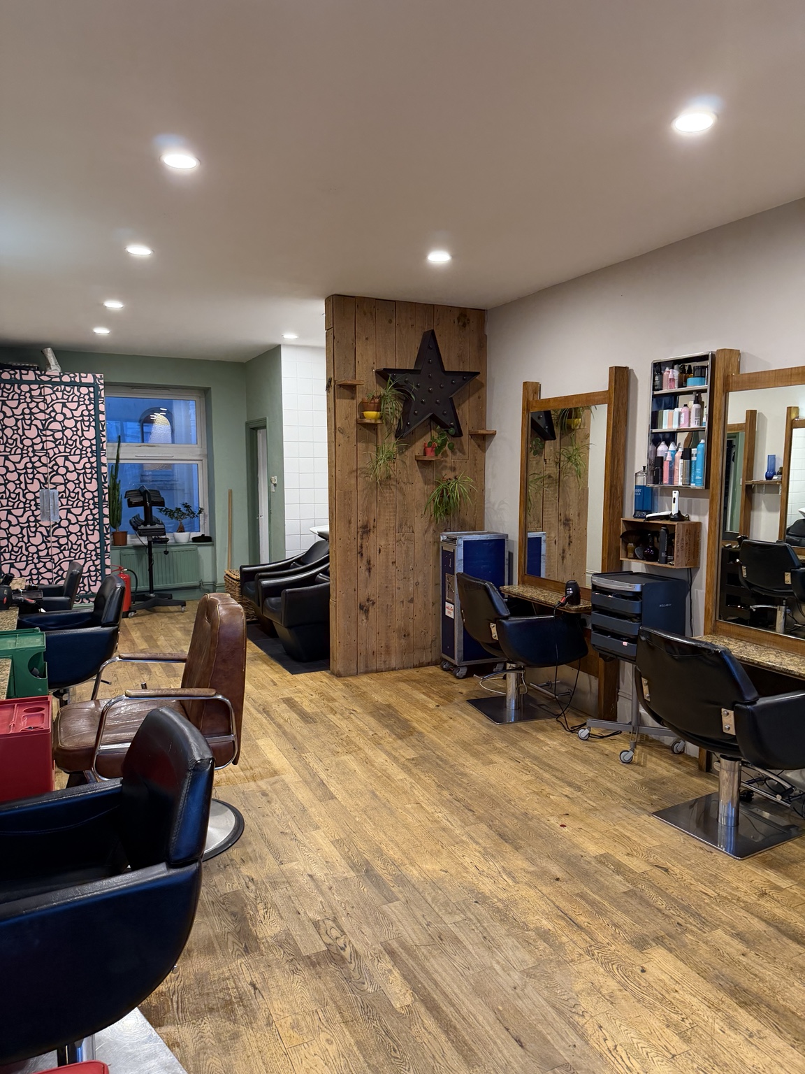 Salon styling area with black chairs, wooden mirrors and a clean floor